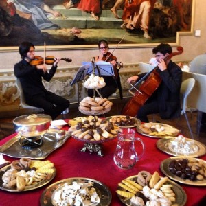 italian pastries on a table with musicians performing around the table 