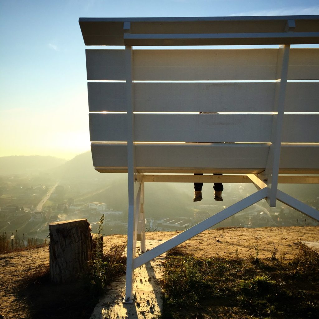 Big bench in Piedmont in white with child sitting on it looking at hill views of Piedmont