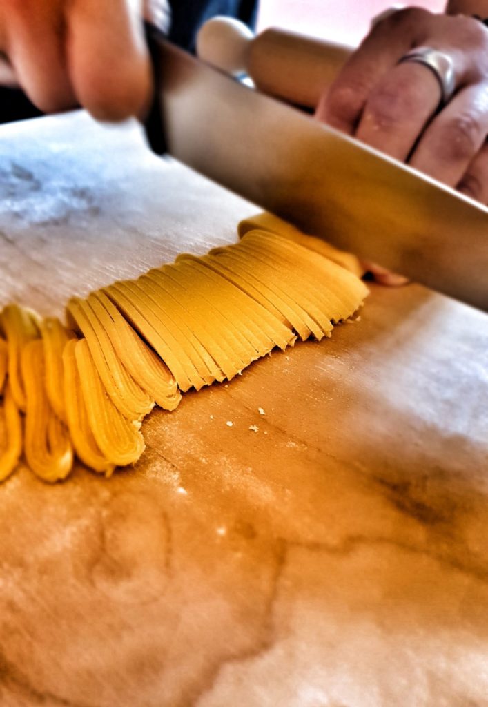 Tajarin pasta being cut into thin pieces 